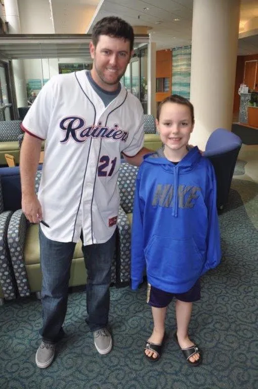 True Competitors founder Casey Coleman, in his Tacoma Rainiers jersey, standing with a smiling young patient